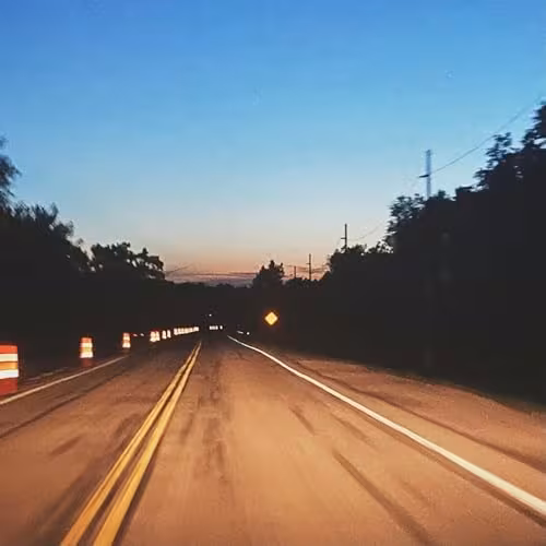 MISTY SKIES cover art - a two-lane road at dusk lined with construction barrels